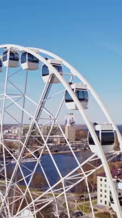 Ferris wheel slowly turning, with city scape of Riga under a clear blue sky
