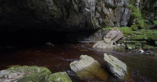 wide shot looking across Porth yr Ogof Cave entrance with the river Mellte