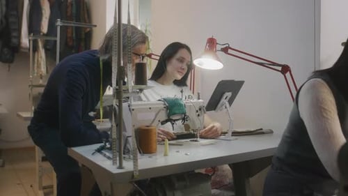 Mature Tailor with Seamstress Discussing Sketch of Suit
