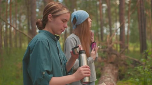 Hikers Enjoy Relaxing Moment in Forest with Thermos and Hair Care