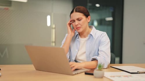 Woman Experiences Headache Working on Laptop in Office