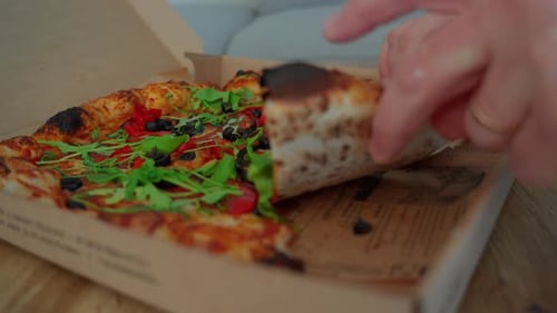 Hand Reaches for Pizza Slice in Box