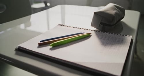Close Up Shot of School Desk with Student School Supplies Pencil Case Pens and Pencils Notebook