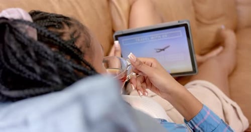 A young African American woman is booking travel on a tablet