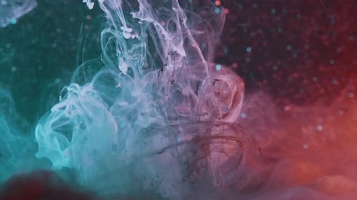 Mix of colors, turquoise, red and black liquid moving inside a water container