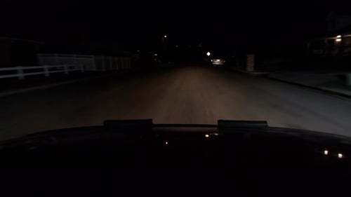 A hood of a car point of view driving at night a dark road headlight show the world.