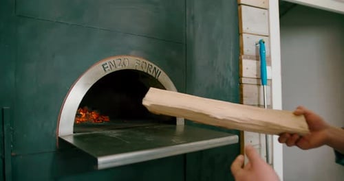 View of a man adding firewood into the burning furnace