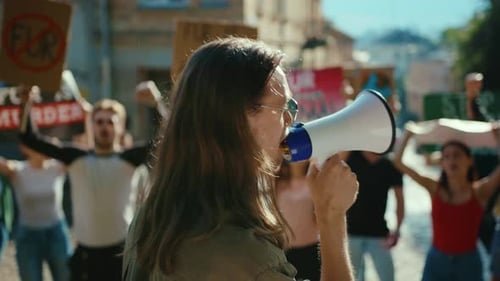 Woman Leads Protest with Megaphone on City Street