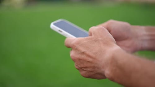 Primer plano de manos caucásicas masculinas escribiendo en la pantalla táctil del teléfono inteligente en cámara lenta
