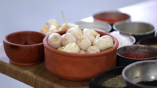 shallots in the casserole and spices on the table