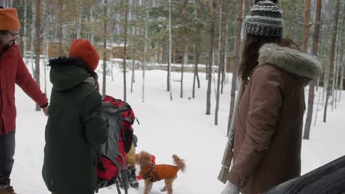 Cheerful Caucasian Family Unloading Bags from Car at Winter Forest
