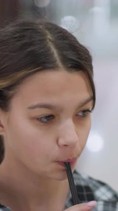 Focused Teen Tasting Drink Mall Closeup Playful Glances Straw Between Lips Plaid Shirt Soft Bokeh
