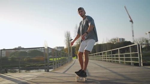 Active Man Riding Skateboard on Bridge Near Sea on Sunny Day