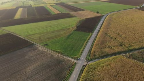 Flying Above a Countryside Road Following a Car Among Agriculture Fields by Drone