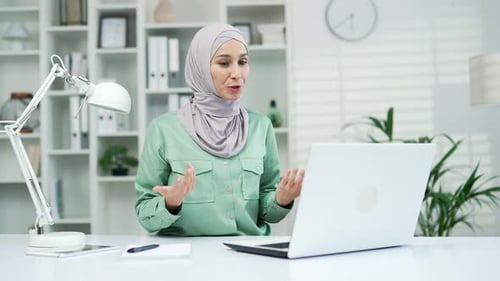 Woman in Headscarf on Video Call at Desk