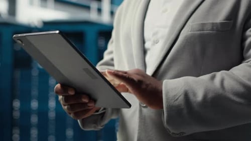 Close Up of System Administrator Walking in Data Center Using Tablet