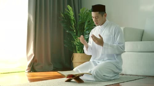 Portrait d'un musulman asiatique récitant le passage de la sourate al-Fatiha du Coran, lors d'une prière quotidienne à ho