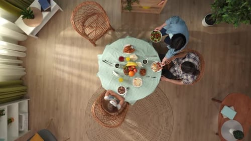 Top View of Mother Small Daughter and Father Sitting at the Table in the Room Eating Breakfast