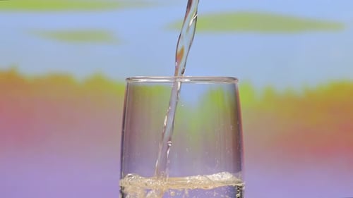 Gros plan de l'eau potable versée dans un verre sur fond d'écran rose naturel dans le studio
