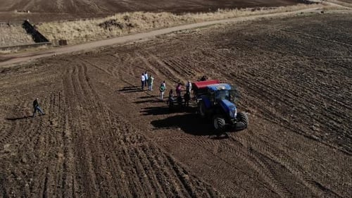 Aerial View of Farm Workers and Tractor in Field