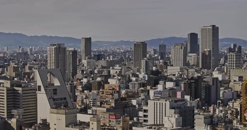 Osaka Japan Aerial v60 zoomed flyover capturing densely populated downtown urban cityscape against