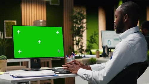 Man Typing on Computer with Green Screen in Office