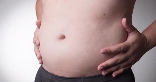 Close-up, male stomach, overweight. Young man with a naked fat belly shakes fat folds on his stomach