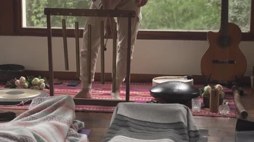 Close up shot of person playing tubular bells inside yoga room. Guitar and other instruments for sou