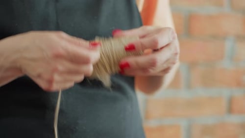Decorator in Black Apron Pulling Natural Twine From Spool