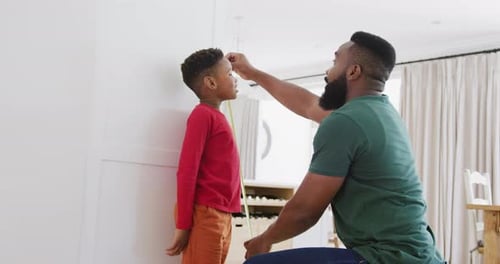 Glücklicher afroamerikanischer Vater und Sohn messen Größe in Zeitlupe