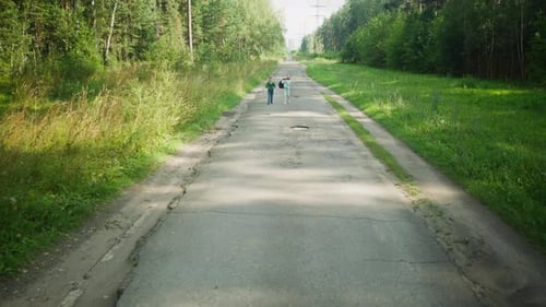 Distant View of Children Walking Home Along Forest Road