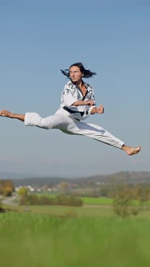 Martial Artist Performing a Flying Kick Outdoors