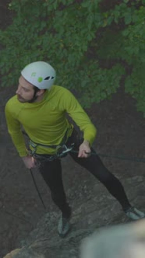 Male Climber Adjusts Safety Gear Outdoors Male Mountaineer Prepares His Ropes with Focus in Wooded