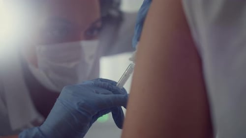 Woman doctor making corona antivirus vaccine injection to patient in hospital