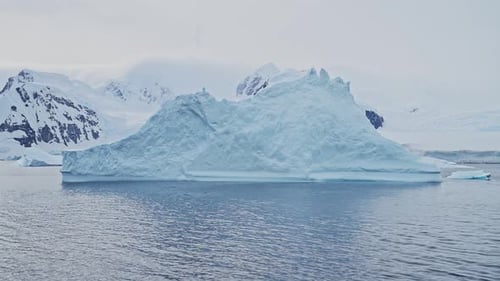 Eisberg, der im Meer auf See schwimmt, mit antarktischen Bergen an der Küste der antarktischen Halbinsel, wunderschönes D