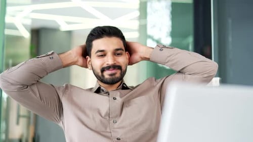 Satisfied bearded businessman finished work on laptop while sitting at workplace in business office.