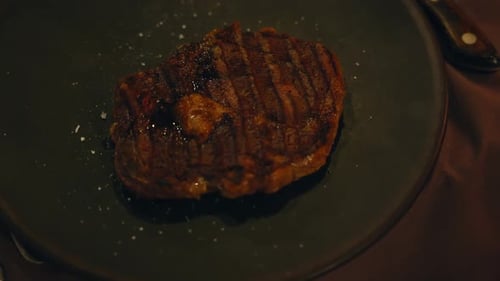 Vídeo em câmera lenta de um bife grelhado servido em um prato com sons escaldantes em alta resolução