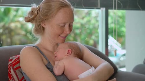 A Young Mother Lovingly Cradles Her Tiny Newborn Baby in Her Arms Sharing a Heartwarming Moment of