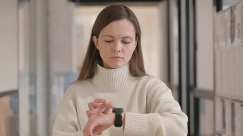 Woman Interacts with Smart Watch in Modern Indoor Setting
