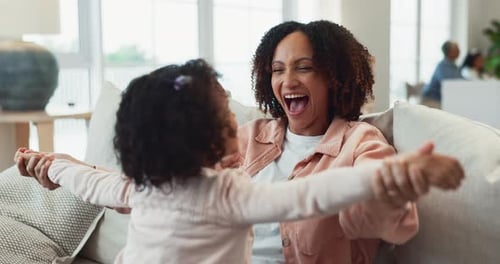 Laughing Woman and Child Play Together on Couch