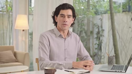 Un emprendedor masculino hace un videoblogueo sobre tecnología sentado con un portátil en el estudio