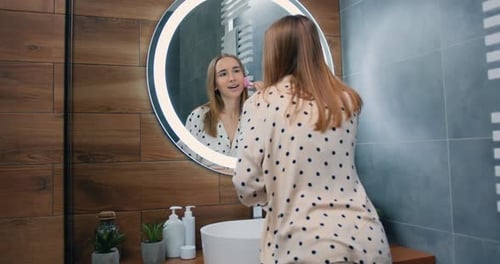 Woman Uses Beauty Roller in Bathroom Mirror