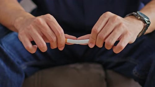 Gros plan des mains de la personne cassant une cigarette en deux