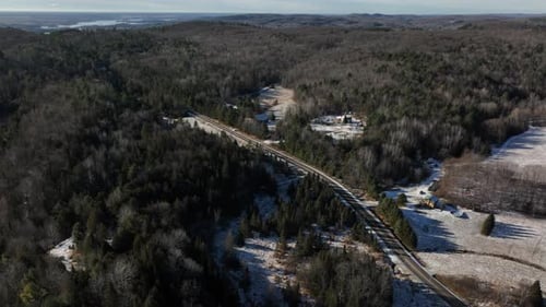 Landstraße und Nadelwald im Winter - Drohnenaufnahme aus der Luft