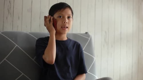 Child Talking on Mobile Phone on Gray Couch