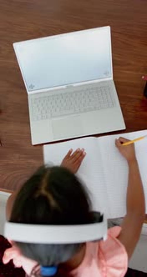 Vertical video overhead of biracial girl having online lesson on laptop with copy space, slow motion
