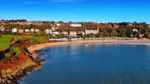 The scene shows a coastline with a clear blue sea and sandy beach.