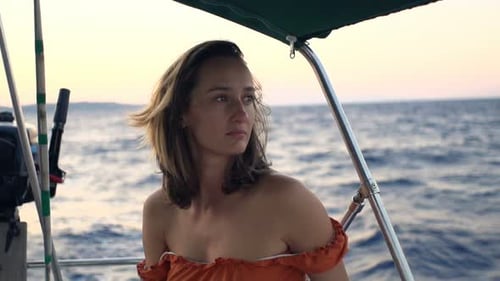 Sad woman sailing on blue sea reflecting on life's difficulties in slow motion
