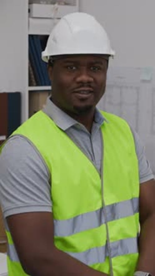 Black Workman in Hardhat Posing for Camera in Construction Office