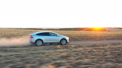 Car Driving on a Dirt Road at Sunset